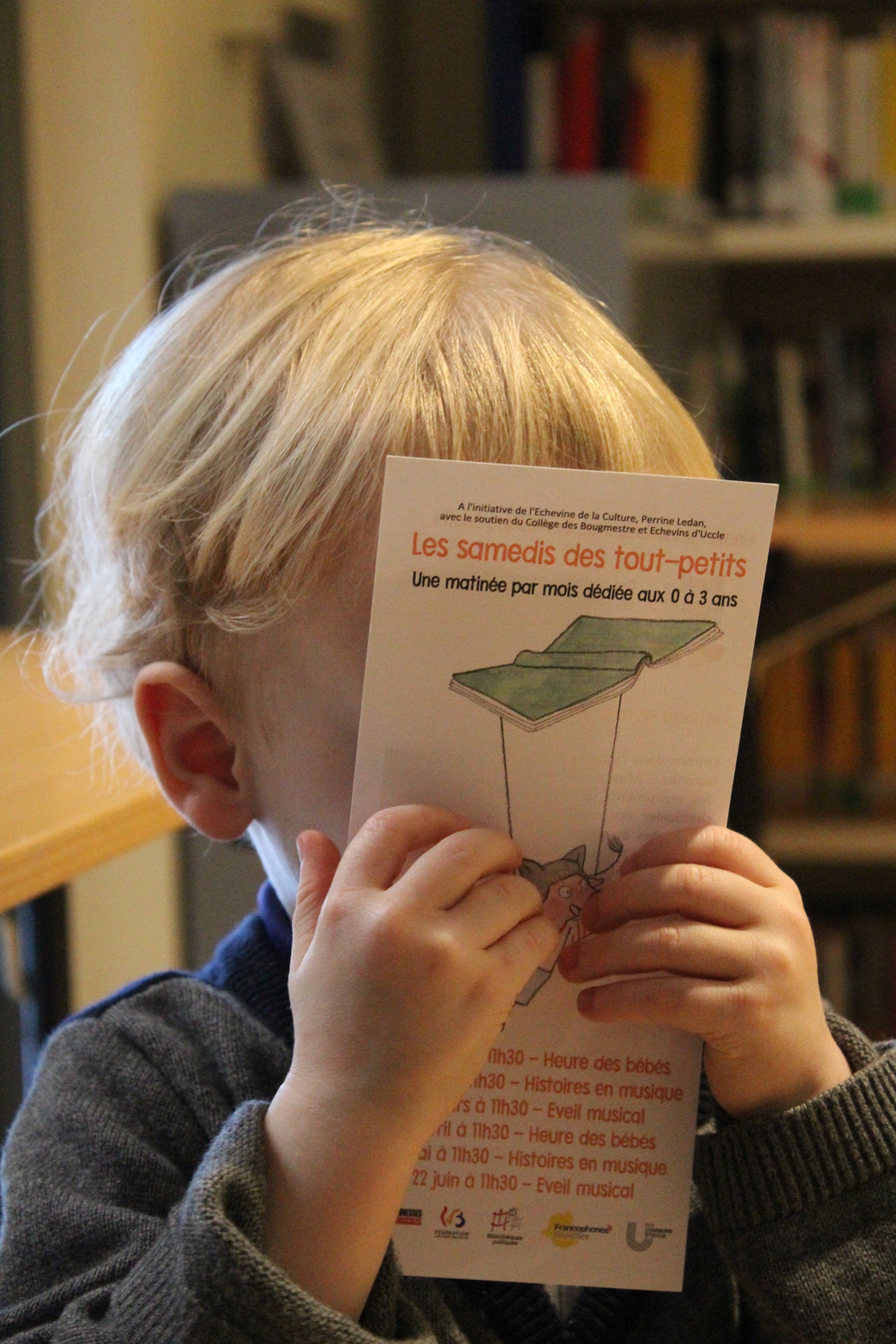 Enfant tenant un flyer devant son visage