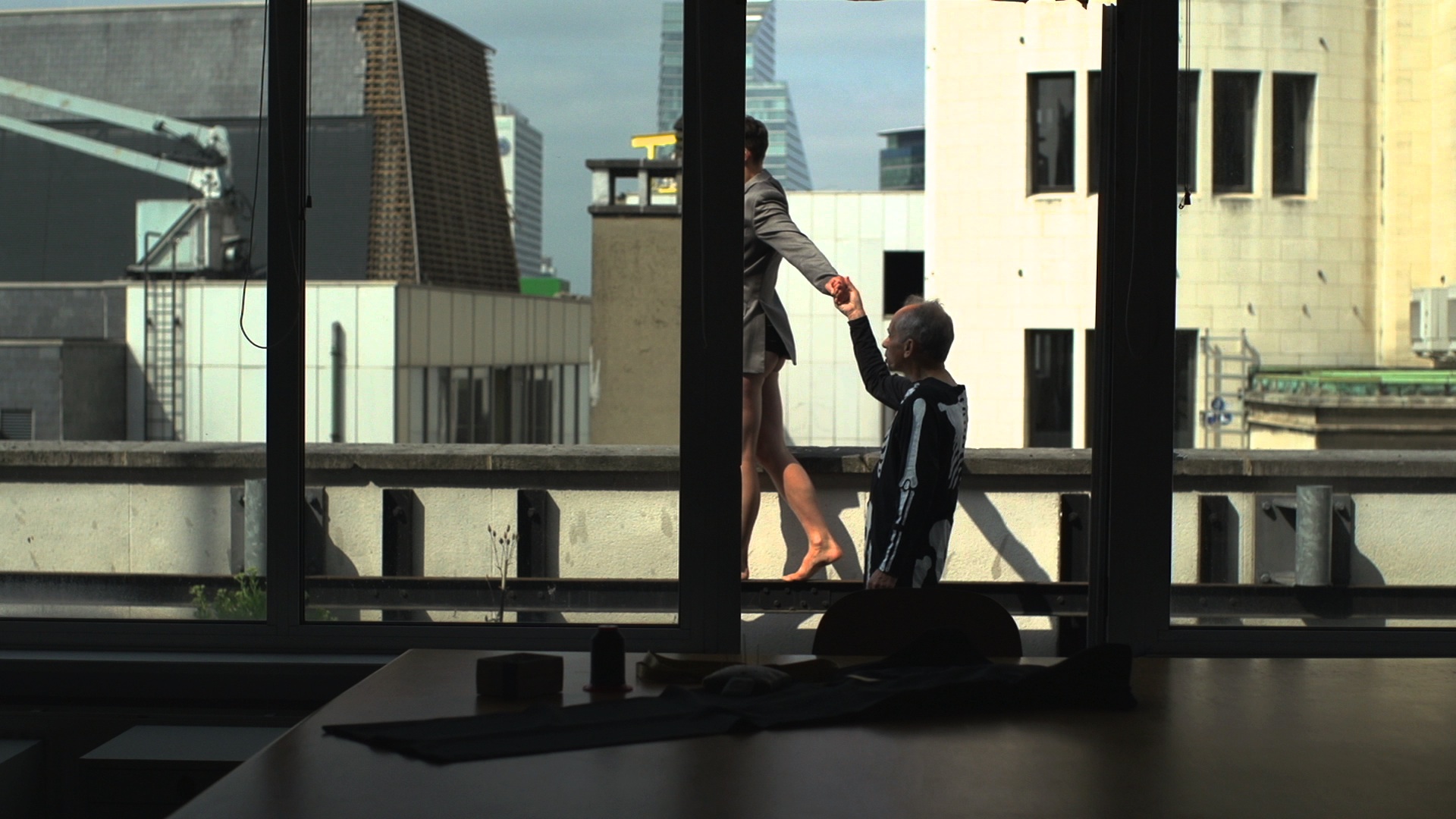 Photo d'une danseuse sur un toit et d'un homme qui la teint par la main